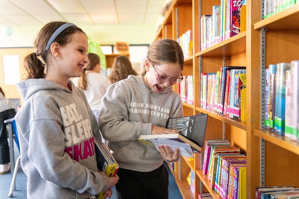 two children looking at books in a library