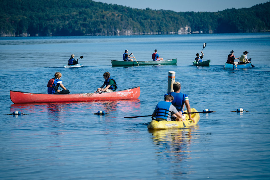 students in kayaks and canoes on the lake